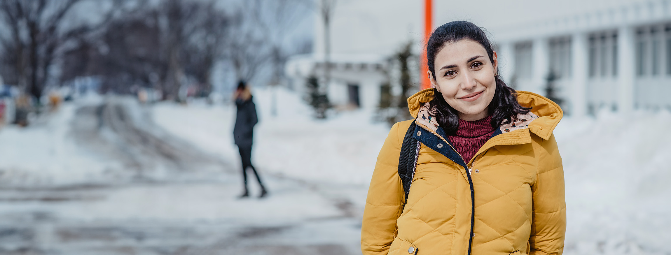 une personne sur le campus devant un pavillon en hiver